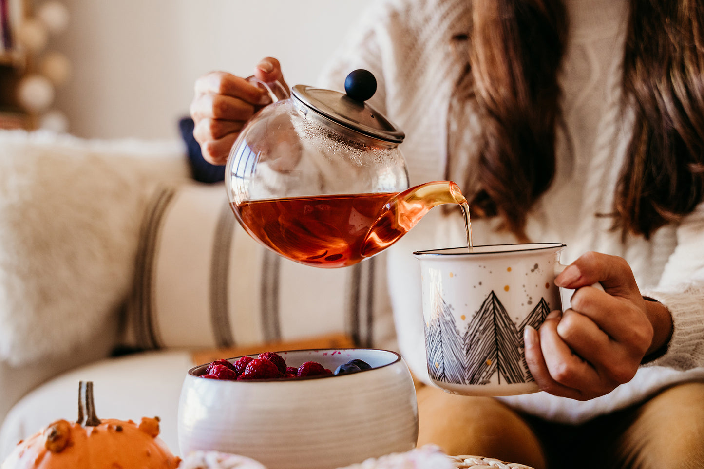 Woman pouring tea from a teapot into a mug