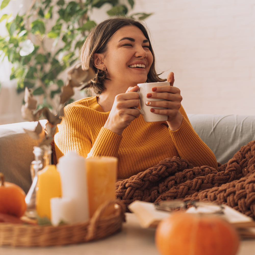 woman on couch holding warm mug of tea