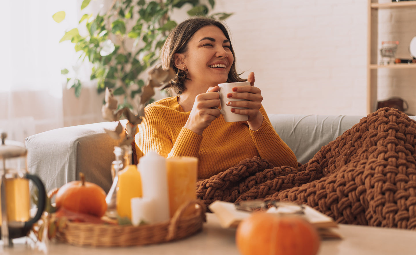 woman on couch holding warm mug of tea